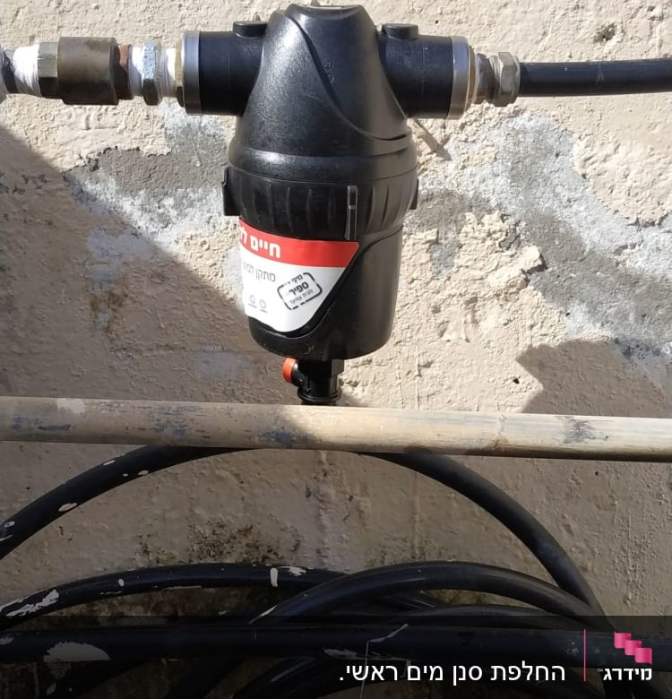 מסנן מים שחור מחובר לצינור על קיר
